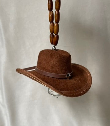 Brown miniature cowboy hat with a brown band hanging from a beaded elastic loop on a white background