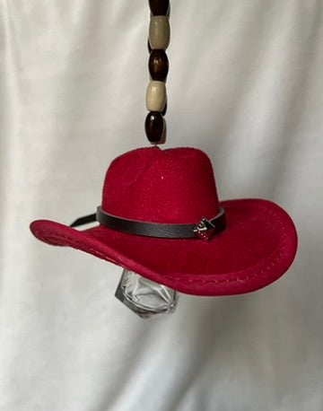 Red miniature cowboy hat with a black band hanging from a beaded elastic loop on a white background